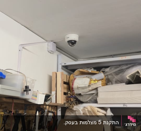 מצלמת אבטחה מותקנת על תקרה במחסן עם כלים וחומרים שונים